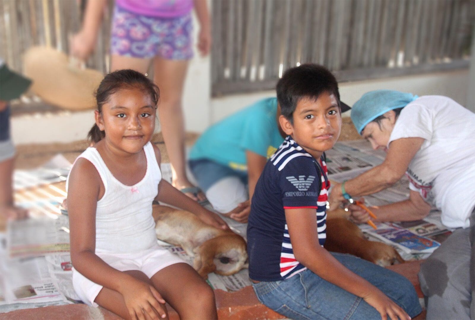 A group of children sitting on the ground with their dogs.