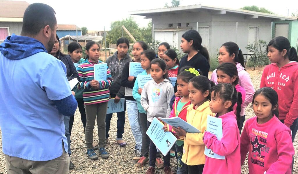 A group of children holding papers in front of a woman.